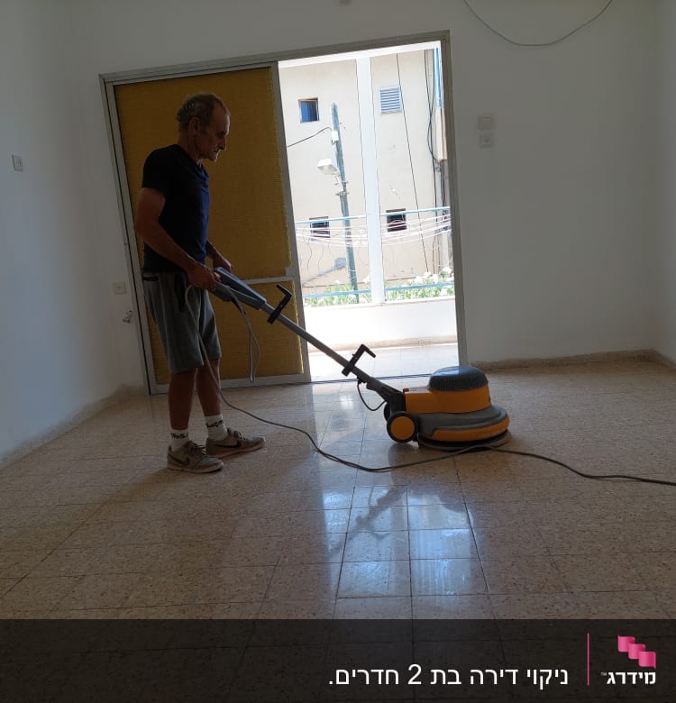 אדם מנקה רצפה עם מכונת פוליש חשמלית